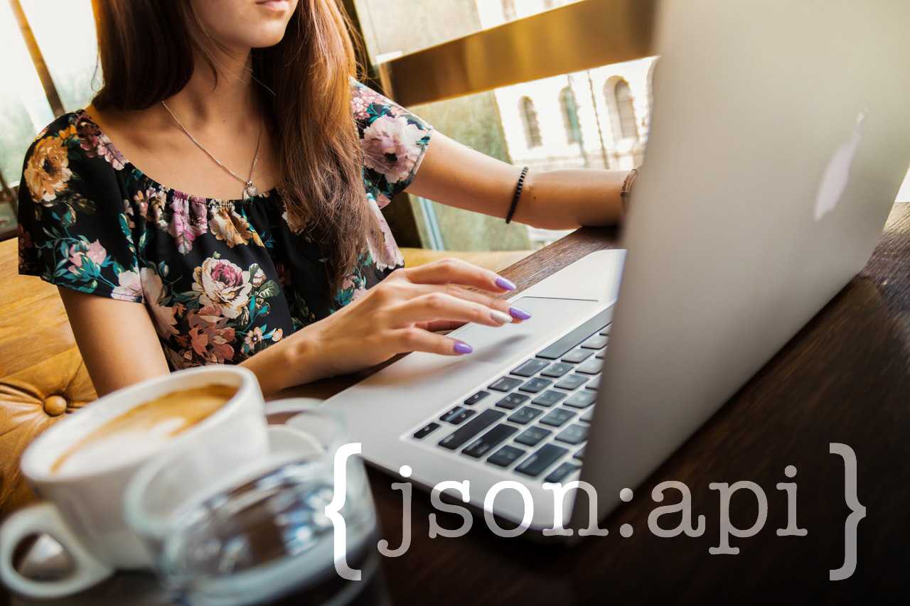 A woman sitting at a computer with a cup of coffee sitting nearby